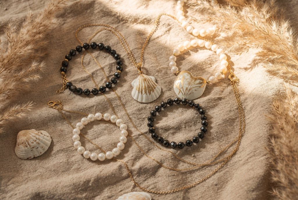 Bijoux bohèmes en porcelaine et perles avec pendentifs coquillage posés sur un tissu de lin beige